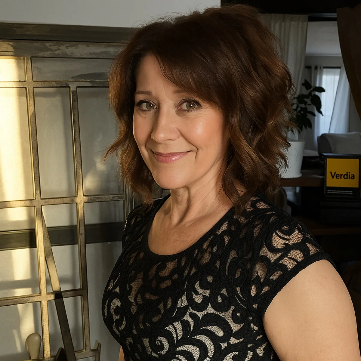 A woman with shoulder-length brown hair, wearing a black lace top, smiles slightly at the camera.